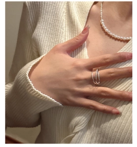 Close-up of minimalist S925 sterling silver layered ring worn with a beige cardigan