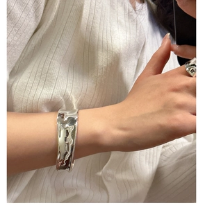 Detail of minimalist S925 sterling silver cuff bracelet and ring with liquid metal texture