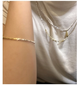 Close-up of a minimalist S925 sterling silver layered necklace and bracelet set on skin