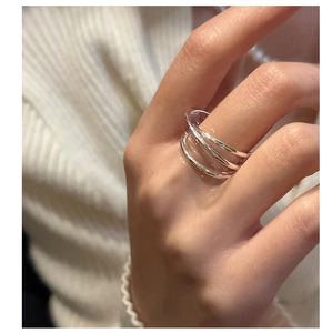 Macro shot of minimalist silver multilayer wrap ring on finger over a knit background