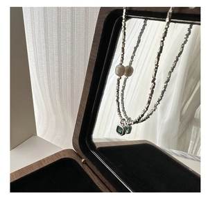 Detail view of S925 silver necklace with green zircon pendant and pearl on jewelry box