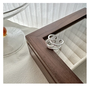 Vue détaillée d'une bague multicouche en argent au design minimaliste sur un écrin en bois