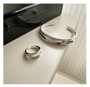 Detail of silver minimalist curved open ring and bracelet set with polished finish