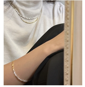 Detail of layered S925 sterling silver necklaces and bracelet on white sweater