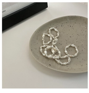 Gros plan de perles baroques et perles argentées sur une assiette en céramique