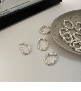 Mise en scène de bagues élastiques en perles baroques et perles d'argent sur céramique