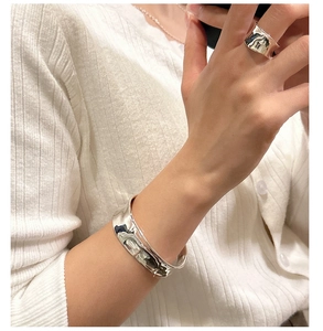 Detail of wavy S925 sterling silver cuff and matching ring with polished hammer texture