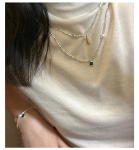 Detail of S925 silver layered necklace with green zircon and pearls on a model