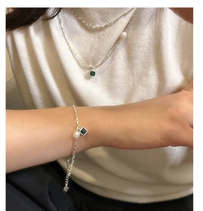 Detailed view of S925 sterling silver bracelet with green zircon and white pearls on wrist