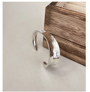Detailed view of silver minimalist bangle with textured water ripple mirror finish surface