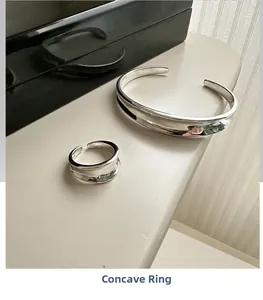 Close-up of polished S925 sterling silver concave cuff bracelet and open ring set