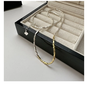 Detail of silver and gold mixed beaded necklace with heart charm and extension chain