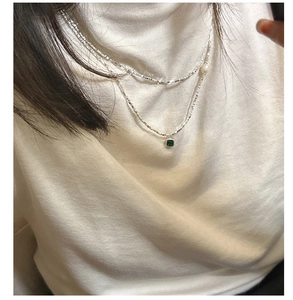 Close-up of double layer silver necklace with square green zircon and pearl on neck