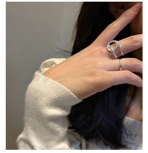 Détail du lot de bagues S925 argent minimalistes torsadées portées sur un pull blanc côtelé