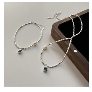 Close-up of S925 sterling silver jewelry set with emerald zircon and white pearl