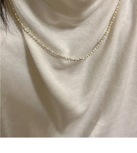 Collier minimaliste en argent S925 bicolore porté sur un col roulé en maille beige