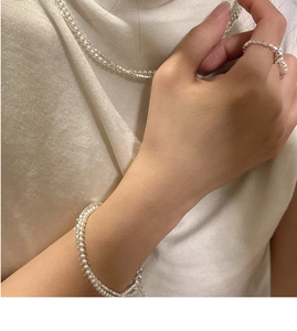 Detail shot of double-layered silver pearl necklace set and bracelet on model