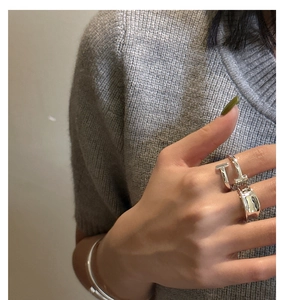 Close-up of minimalist S925 sterling silver rings and cuff bracelet on model hand