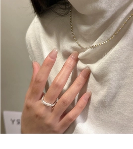 Détail d'un collier bicolore minimaliste assorti à une bague en perles sur un mannequin