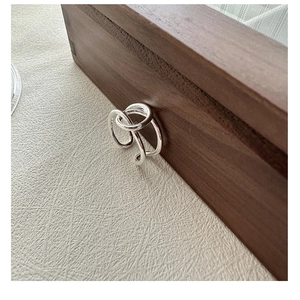 Détail de la bague multicouche minimaliste en argent S925 sur une boîte en noyer