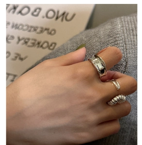Detailed view of three-piece silver ring set with textured surfaces on a model hand