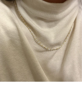 Vue détaillée du collier minimaliste bicolore or et argent sur un pull blanc