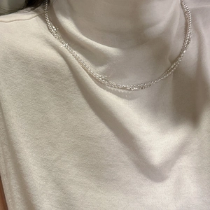 Double-layered S925 sterling silver necklace with delicate pearls on a white knit sweater