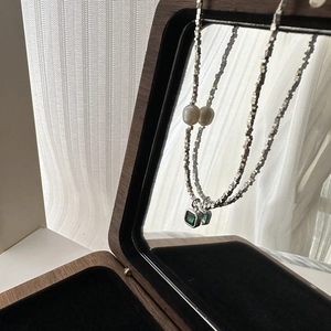 Vintage S925 silver necklace featuring green zircon pendant and pearls on wooden mirror