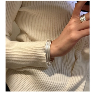 Vue détaillée du bracelet multicouche en argent S925 mat et bague texturée sur tricot
