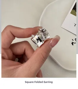 Detail view of square silver hoop earrings with a unique textured crumpled finish