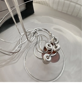 Macro detail of silver snake chain necklace with frosted donut-shaped pendant rings