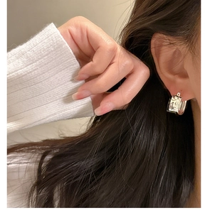 Detail of silver hoop earrings with irregular lava texture worn by a model in close-up