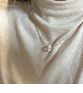 Detailed view of an S925 sterling silver donut pendant on a snake chain against a sweater