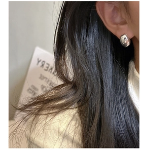 Close-up of a high-polished S925 sterling silver bean stud earring worn on the ear