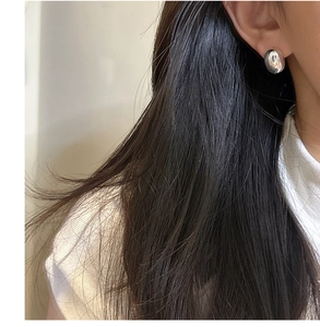 Close-up of minimalist pebble-shaped S925 sterling silver stud earrings on model's ear