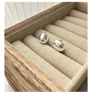 Macro shot of silver bean earrings with mirror finish on a natural linen jewelry box