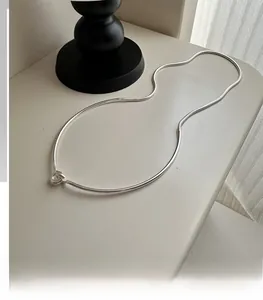 Detail shot of a minimalist S925 sterling silver snake chain necklace with knot design