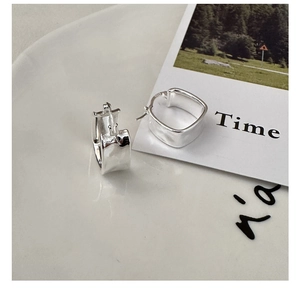 Close-up of S925 sterling silver square hoop earrings with hammered texture on white plate