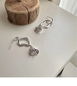 Macro detail of S925 silver calla lily earrings with a modern fluid metal wave design