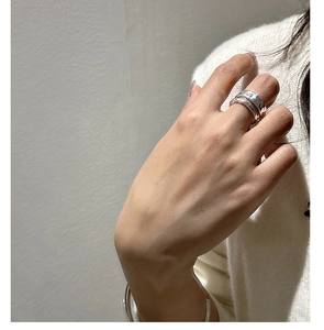 Close-up of a silver S925 layered textured ring and minimalist open cuff bracelet on hand