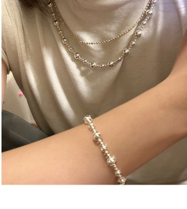 Détail de l'ensemble collier et bracelet à billes en argent S925 sur un t-shirt blanc