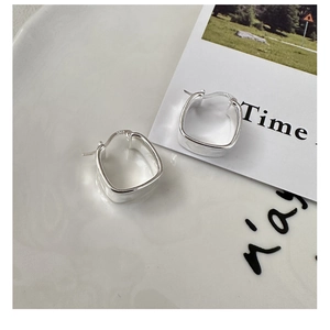 Macro detail of S925 sterling silver square earrings with polished texture in a ceramic tray
