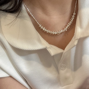 Irregular silver crushed bead necklace shown on a model wearing a white collar top