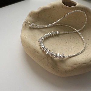 Minimalist S925 sterling silver necklace with irregular silver beads on a ceramic tray