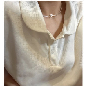 Close-up of S925 sterling silver snake chain necklace with a minimalist knot on a white polo
