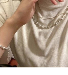 Détail de l'ensemble collier et bracelet en argent S925 sur un pull en tricot blanc