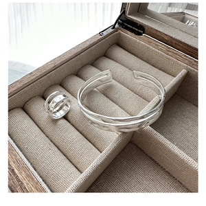 Close-up of hammered silver double-layer ring and matching cuff on a linen display