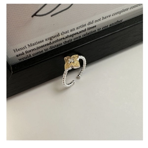 Detail of S925 silver rope ring with golden four-leaf clover on a minimalist background