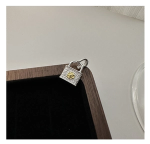Macro detail of silver lock pendant featuring floral engraving and gold flower accent
