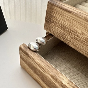 Polished S925 sterling silver oval stud earrings displayed on a wooden jewelry box